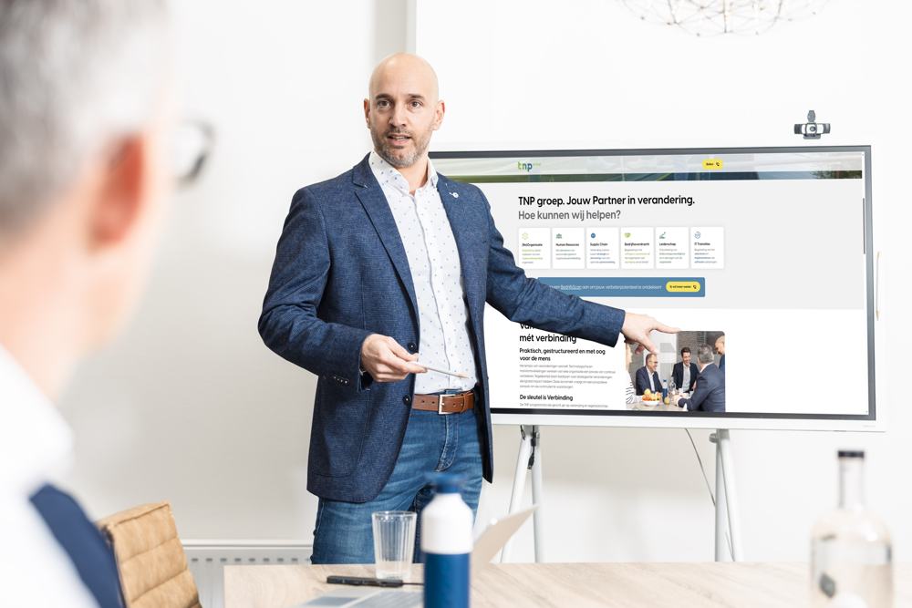 Een adviseur wijst op een scherm tijdens een workshop